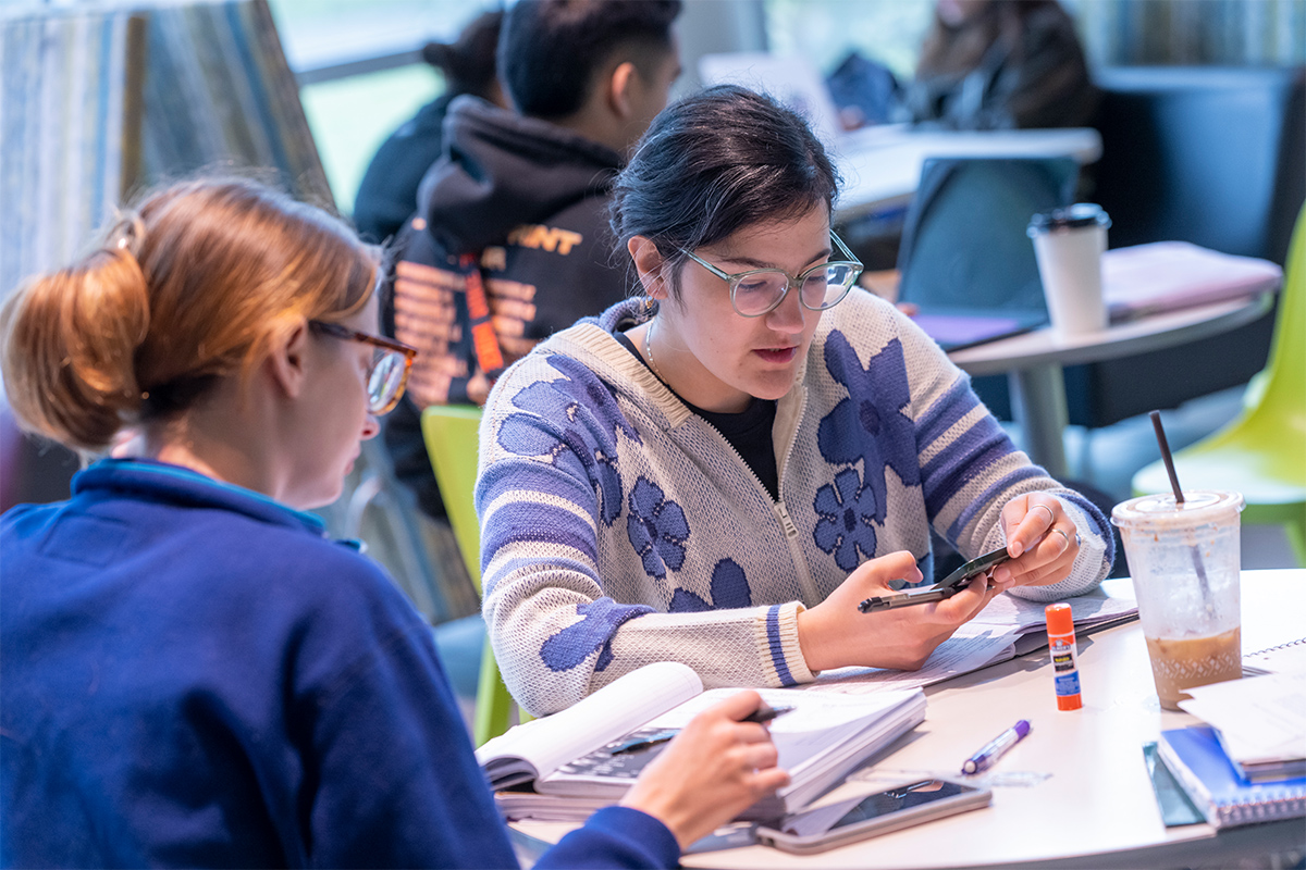 Students at table with books and phones