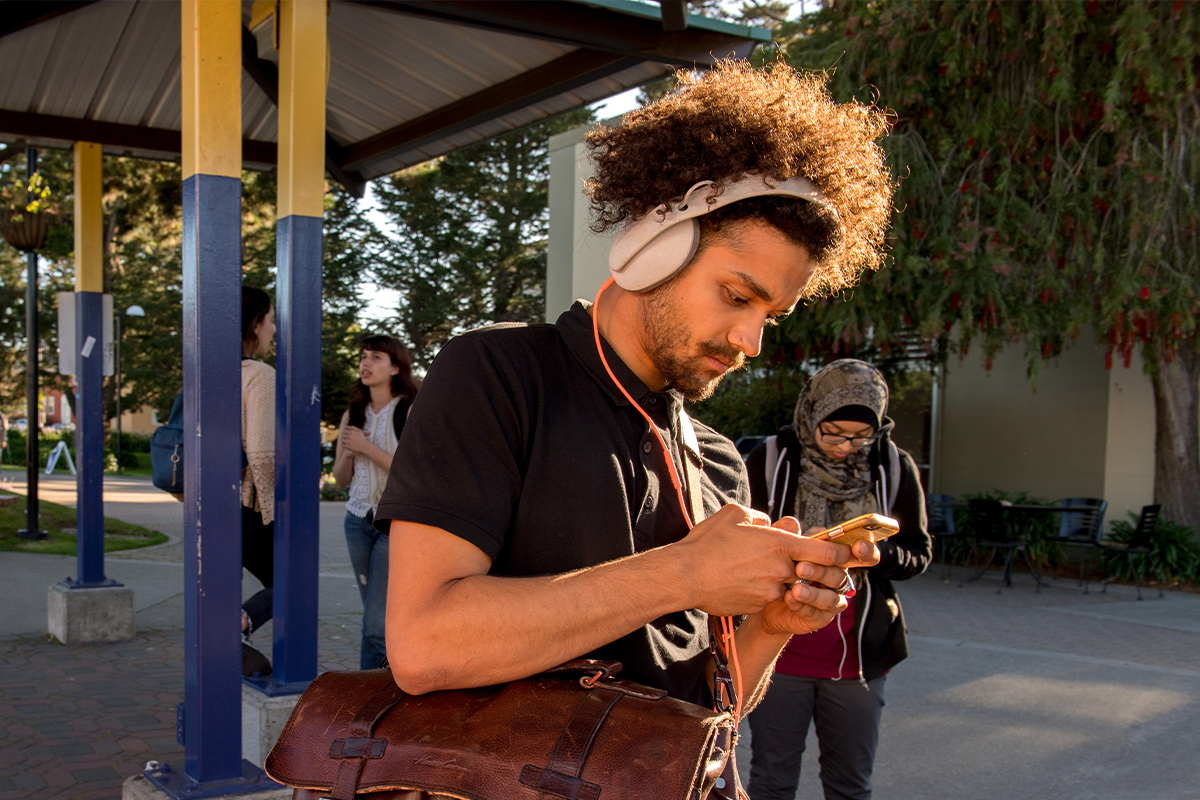 Student with headphones looking at phone